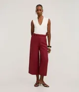 Pantalón tipo pantacourt de corte sastre, color rojo oscuro o vino, con talle alto y lazo ajustable en la cintura. El tejido es ligero y fluido.
