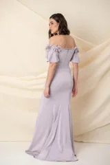 Vestido largo de crepé de seda color lila, modelo entallado con falda con vuelo. Mangas cortas con apliques de flores de tela, organza y plumas.