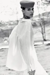 Blusa blanca confeccionada en lino, con cuello polo, escote en V y mangas largas amplias. Presenta un diseño holgado y bajo asimétrico.