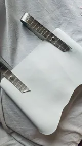 Top corto de ecocuero negro con corte asimétrico y un tirante ancho de ecocuero blanco con textura de piel de cocodrilo. Se ajusta con botones o lazo en la espalda.