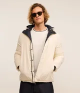 Campera puffer de hombre reversible, con diseño acolchado, cuello alto, capucha y cierre frontal.