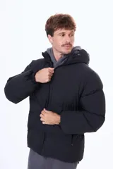 Campera puffer negra con capucha, cierre frontal y puños elásticos. Diseño acolchado con relleno térmico y exterior de nylon resistente.