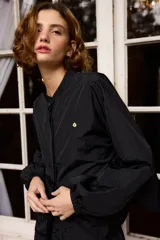 Camisa de nylon color bordó, de corte holgado y diseño minimalista con mangas largas abullonadas y puños elásticos.