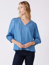 Blusa Zac & Rachel de lyocell color azul, con escote en V y panel central con pespuntes. Presenta mangas tres cuartos abullonadas con frunces en los hombros y puños elastizados con detalle de volante.