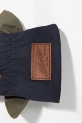 Guantes de diseño patchwork en tonos marrón, verde oliva y azul marino, con detalle de lazo decorativo en la muñeca.