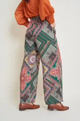 Pantalón italiano de seda con estampado geométrico en tonos verde, rosa, amarillo y negro. Tiene cintura elastizada y bolsillos laterales.