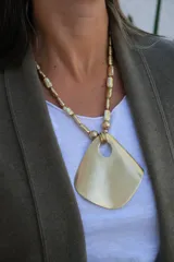 Collar de diseño artesanal con cadena compuesta por cuentas metálicas texturadas y dije central grande de forma irregular con acabado mate.