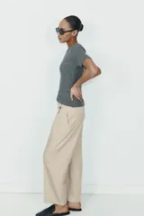 Pantalón de tiro alto con corte recto, bolsillos delanteros y detalle de pinzas con botones en la cintura. Cuenta con cierre frontal de cremallera y gancho metálico.