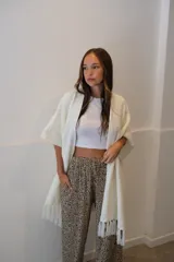 Ruana negra de tejido liviano con terminación de flecos en el ruedo y mangas amplias.