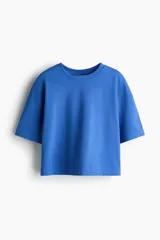 Remera de corte boxy y holgado, color azul, confeccionada en suave punto de algodón. Presenta cuello redondo, hombros caídos y mangas cortas que llegan hasta el codo.