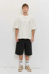 Remera marrón oversize de manga corta, con cuello redondo y pequeños estampados blancos en el pecho.