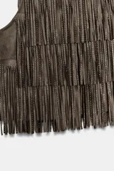 Top corto sin mangas de cuello redondo, confeccionado en tejido tipo gamuza con múltiples capas de flecos decorados con aplicaciones de brillos. Cuenta con cierre posterior oculto.