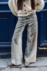 Pantalón de denim tiro medio con silueta amplia y corte recto. Presenta un diseño bicolor con estampado tipo animal print en tonos grisáceos y marrones, con bolsillos laterales y traseros.