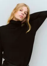 Vestido corto de punto negro con cuello alto vuelto y mangas largas de corte recto.