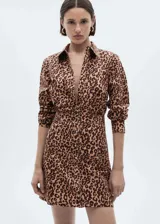 Vestido corto estilo camisero con estampado de leopardo, cuello camisero, cierre frontal con botones y mangas largas con puños abotonados.