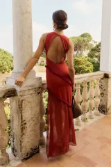 Vestido largo color caldera, sin mangas, con escote redondo y drapeado en el cuello. Presenta un detalle de volados con flecos en diagonal a lo largo del cuerpo.