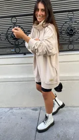 Buzo color beige de algodón con cierre frontal, cuello alto y bolsillo escondido.