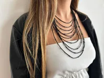 Collar de múltiples hilos negros con tubitos y cadena trasera para regular el largo.