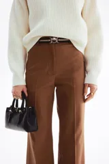 Pantalón bootcut color marrón, tiro alto, con pliegues frontales y cinturón elástico incluido con hebilla metálica redonda.