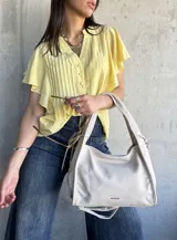 Camisa amarilla de mangas cortas con volados, cuello mao y botones frontales.