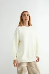 Buzo de tejido de punto en color blanco, con cuello redondo, mangas largas y corte holgado.