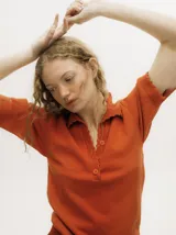 Chomba color naranja de algodón, con terminación en crochet en el cuello, puños y ruedo. Tiene escote cavado y abotonado.