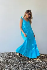 Vestido largo celeste con breteles finos con detalle de nudo y falda con volados.
