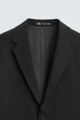 Blazer slim fit de color negro, confeccionada en tejido con viscosa. Presenta cuello con solapas de muesca, cierre frontal con botones, bolsillo de vivo en el pecho y bolsillos de solapa en la cadera.