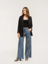 Pantalón de jean elastizado azul con terminación metalizada, corte wide leg, tiro medio, cierre delantero con botón, bolsillos laterales y traseros.