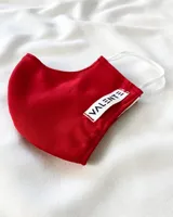 Tapabocas rojo con elástico blanco y etiqueta con la marca "Valente".