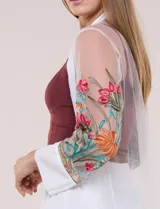 Cardigan tipo kimono largo de tul blanco semitransparente, con frente abierto y mangas largas. Presenta vistosos bordados florales multicolor en mangas, dobladillo y laterales.