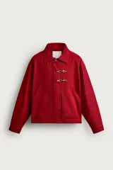 Cazadora relaxed fit de Zara confeccionada en tejido de algodón rojo con efecto lavado. Presenta cuello solapa, manga larga, bolsillos de plastrón en la cadera y cierre frontal de cremallera oculta con solapa y alamares metálicos.