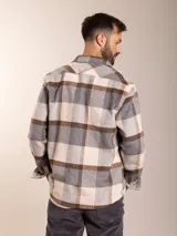 Camisa de franela a cuadros en tonos beige, gris y marrón, con corte regular fit, cuello clásico, cierre de botones frontales y dos bolsillos con solapa en el pecho.