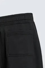 Pantalón jogger de corte relajado y pernera ancha, confeccionado en tejido de algodón con interior perchado. Cuenta con cintura elástica ajustable mediante cordón interior, bolsillos laterales y un bolsillo trasero de plastrón.