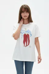 Remera de algodón color beige con estampado frontal de un corazón rosado que contiene un moño. Tiene cuello redondo y mangas cortas.