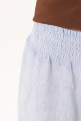 Pantalón palazzo celeste de tiro alto, con cintura elástica fruncida y diseño amplio de pernera ancha.