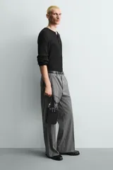 Bandolera negra con textura grabada, forma rectangular y cierre de cremallera. Tiene un bolsillo interior plano y otro frontal plano. Incluye asa de hombro ajustable y extraíble.