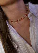 Gargantilla tipo choker compuesta por pequeñas cuentas de vidrio en tono dorado translúcido, intercaladas con cuentas más grandes de color rojo.