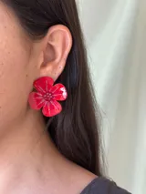 Aro con forma de flor pintada a mano, con pétalos en tonos fucsia y detalles de brillo, y centro decorado con mostacillas.