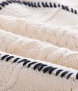 Suéter de cuello redondo y manga larga, confeccionado en tejido de punto con textura de ochos y detalles lineales en contraste. Presenta puños y ruedo acanalados.