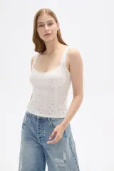 Top sin mangas confeccionado en algodón con diseño de broderie, corte al cuerpo y escote redondo con detalle de puntilla en los bordes.