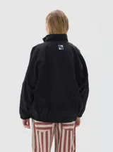 Campera de jean con diseño color block en negro y beige, corte oversized, cuello alto, cierre frontal y bolsillos laterales con cierre. Presenta detalles de costuras visibles y logo de la marca estampado en el pecho.