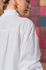 Camisa blanca de algodón con corte amplio, tablitas en la parte delantera y volados en el cuello.