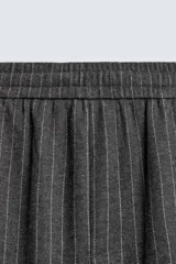Pantalón de corte baggy fit, color gris oscuro con estampado de rayas verticales finas. Presenta cintura elástica con cordón interior, bolsillos frontales de vivo y bolsillos traseros de plastrón.
