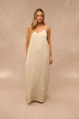 Vestido largo beige de corte recto y holgado, con tirantes finos y escote en V. Presenta un sutil estampado de flores en tono más claro a lo largo de la prenda.