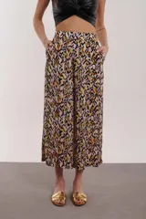 Pantalón capri de tiro alto con estampado abstracto en tonos lila, negro, naranja y amarillo.