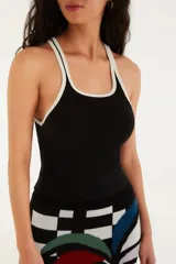 Top tipo musculosa de tejido acanalado blanco, con escote cuadrado y ribetes negros en el borde del escote y las sisas. Presenta doble tirante fino negro.