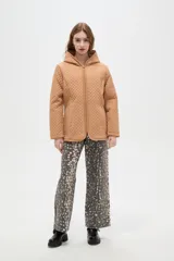 Campera de diseño capitoneado con cierre frontal, capucha integrada y bolsillos laterales. Presenta un corte entallado y mangas largas.