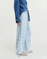 Pantalón celeste de denim camisero liviano, corte pijama relajado, con cintura elastizada y tira de ajuste. Tiene bolsillos laterales, recortes en rodilla, cintura al corte con efecto deshilachado, jareta con tiras para regular en el ruedo y bolsillo plaqué en la espalda.