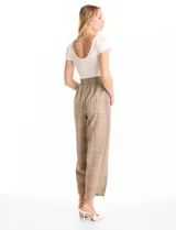Enterito de diseño combinado con remera de cuello redondo y manga corta en color crema, integrada a un pantalón de corte recto y tiro alto con estampado a cuadros. Presenta cintura elastizada y bolsillos laterales inclinados.